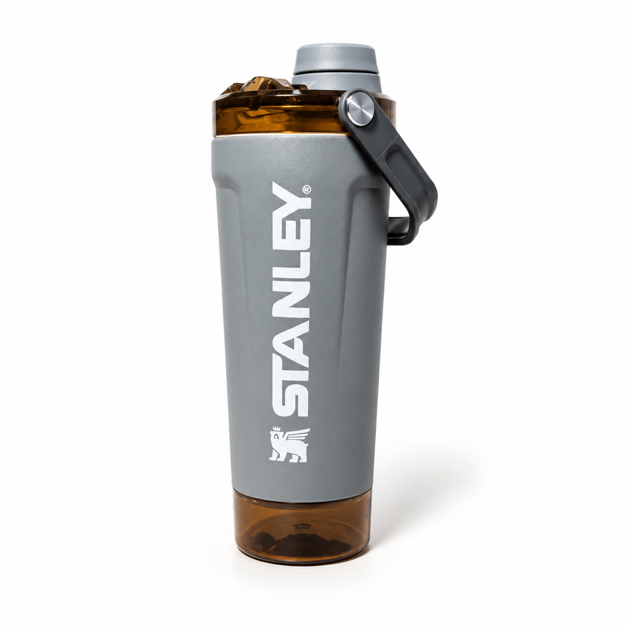 A Stanley shaker bottle with a gray body, white vertical STANLEY logo, a black carrying loop, and a translucent amber-brown base and top section, shown on a white background.